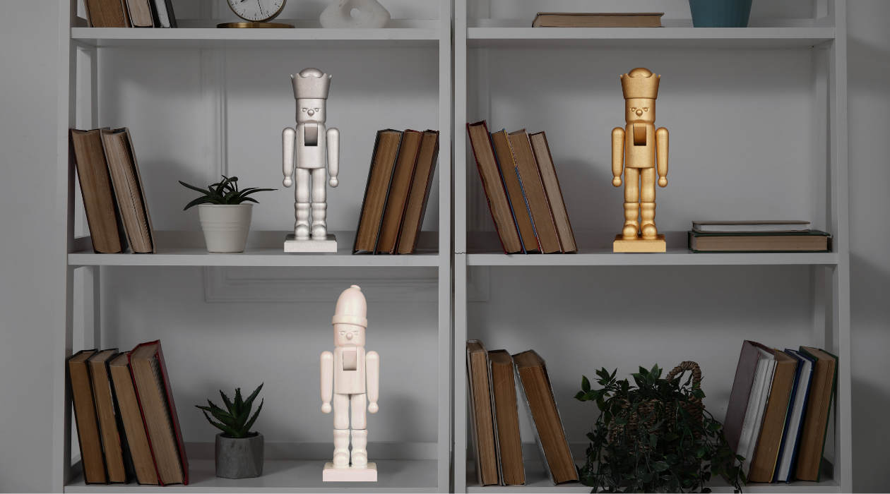Drei Nussknacker der Magic Glimmer-Serie von Christian Ulbricht – in Gold, Silber und Weiß – dekorativ in einem Bücherregal zwischen Pflanzen und Büchern arrangiert.